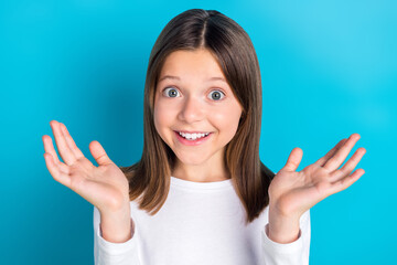 Wall Mural - Photo of satisfied girl with long hairstyle wear white long sleeve raising palms astonished staring isolated on blue color background