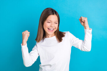Photo portrait of charming schoolgirl raise fists scream yes celebrate dressed stylish white clothes isolated on blue color background