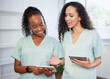 © Meeko Media - Two young women in the medical field wearing scrubs discuss with digital tablets