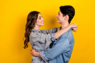 Wall Mural - Profile portrait of two lovely cute partners cuddle look each other isolated on yellow color background