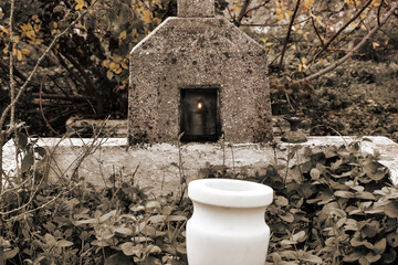 Wall Mural - A nameless orthodox tombstone alone among the trees in autumn. An oil lamp is burning inside the tombstone