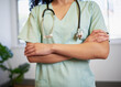 Cropped close up of doctor's arms folded holding stethoscope modern office
