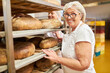 © Robert Kneschke - Baker with experience in front of a shelf with a selection of breads