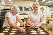 © Robert Kneschke - Baker apprentice with a colleague baking yeast plaited bread