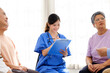 © artitwpd - The caregiver therapist sits with a group of Asian senior people in a circle for checking physical and mental health in a group elderly therapy session. The nursing home facilitates a support group