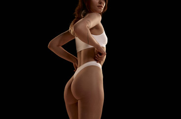 Side view image of cropped female body, buttocks in underwear against black studio background. Anti-cellulite care. Concept of body and skin care, figure, fitness, health, wellness.