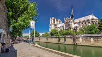 Wall Mural - Notre Dame de Paris timelapse hyperlapse is the one of the most famous symbols of Paris. Boat station on the right. View from Siene waterfront at sunny summer day