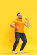 © Lustre Art Group  - Emotional exciting man wearing headphones listening music and dancing with hands over yellow background