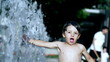 Happy kid having fun at water park jets in 120fps slow motion during heat summer day