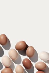 Wall Mural - Easter eggs trend pattern on white background shadow at sunlight. Chicken eggs with beige gradient color eggshells, food Easter festive concept, top view, aesthetic flat lay minimal style