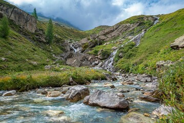 A river streaming in a middle of a green landscape in the Tour Du Mount Blanc