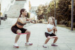 An athletic mother trains with her daughter. Workout with fitness rubber bands outdoors, healthy lifestyle, fitness active family concept. Workout together, physical education