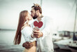 © splitov27 - Young kissing loving couple holding red heart, showing their love in yacht club. Romantic, love concept
