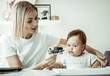 © splitov27 - A caring mother feeds her baby from a spoon while sitting at a table