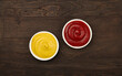 Bowls of tomato ketchup and mustard on table