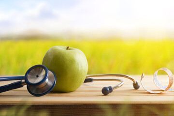 Wall Mural - Health concept with apple stethoscope and tape measure in nature