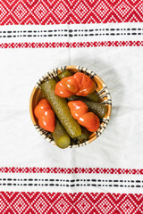 Wall Mural - Mixed pickles of cucumbers and red bell peppers. Pickles in Romanian traditional clay bowl. Top view.