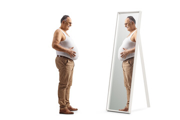 Canvas Print - Full length profile shot of a mature man in an underwear vest looking at his big belly in a mirror