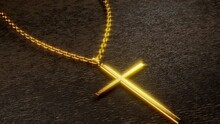 A Golden Crucifix Necklace Shining Brightly On A Black Wooden Desk As The Sunlight Flickered.