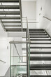 Light design stairs made of stainless steel, tempered glass, steel railings, windows, landings and steps made of polished black granite in an office building