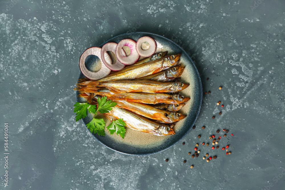 Plate with delicious smoked capelin on grey grunge background