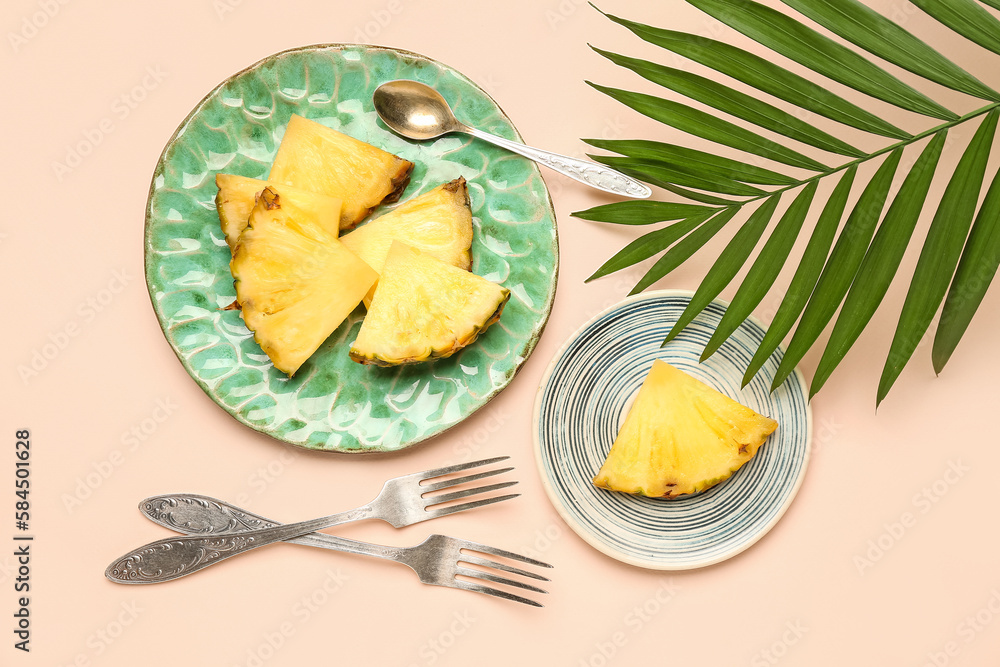 Plate with cut pineapple and palm leaf on light background
