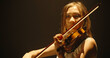 © andreybiling - Experienced asian female violin player having a solo during the concert, spotted by light on black background