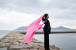 © peach100 - 海でピンクの布を持った女性