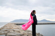 © peach100 - 海でピンクの布を持った女性