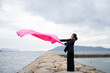 © peach100 - 海でピンクの布を持った女性