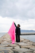 © peach100 - 海でピンクの布を持った女性