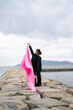© peach100 - 海でピンクの布を持った女性