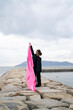 © peach100 - 海でピンクの布を持った女性