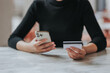 © Witoon - online payment Young woman's hand holding a credit card and using a smartphone for online shopping.