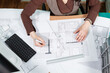 © DC Studio - Over top view of architect working at her desk with blueprints in front of her. Working on new projects. Architecture and design