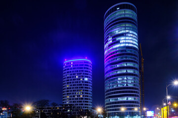 High-rise buildings captured with long exposure. Two illuminated skyscrapers in the evening