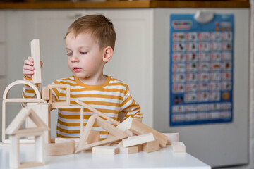 A little boy of 3 years old is playing a developing logistics constructor. Children's wooden toys. Montessori for child development.