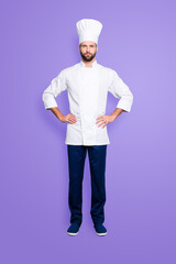 Canvas Print - Full size fullbody portrait of attractive harsh chef cook with stubble in beret, holding arms on waist, isolated over grey background, looking at camera