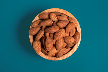 Wall Mural - Almonds in wooden bowl on blue background