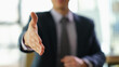 © H_Ko - Businessman in suit extending his hand for handshake to partner at work in office closeup