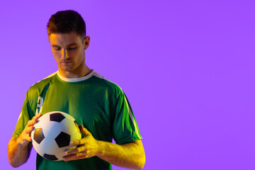 Wall Mural - Caucasian male soccer player with football over neon pink lighting