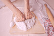 Elderly woman hands rolling out dough in flour with rolling pin in her home kitchen. Close-up of overworked old woman hands making home made baking, pastry and cookery.