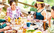 Young friends on healthy pic nic break fast with cute puppy at countryside farm house - Unplug life style concept with happy people having fun together out side at garden picnic party - Focus on dog