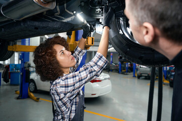 Wall Mural - Multiracial female auto mechanic in overalls and client inspecting car