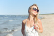 © rogerphoto - Happy blonde woman in free happiness bliss on ocean beach standing with sun glasses