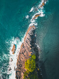 Fototapeta Do pokoju - Aerial drone photo of an island
Serene island of rock with plants and coconut trees on top, surrounded by the crashing waves of the ocean, captured in stunning detail from an aerial drone view