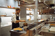 © Manu Padilla/Stocksy - Man mixing food in pan in restaurant kitchen