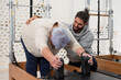 © Bisual Studio/Stocksy - Pilates trainer helping elderly woman