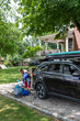 © Raymond Forbes LLC/Stocksy - Packing luggage in car driveway  for family road trip