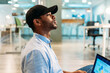 © VICTOR TORRES/Stocksy - Attentive black looking away while using laptop in office